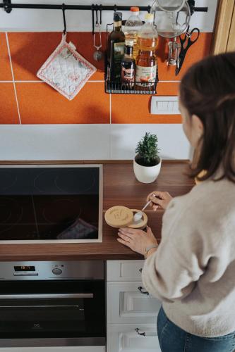 a woman standing in a kitchen preparing food at Apartments Možinetova hiša in Šentjošt nad Horjulom