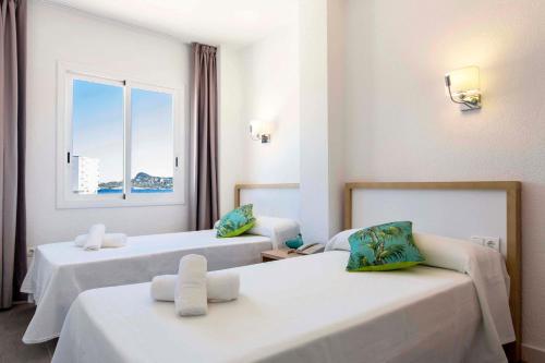 a hotel room with two beds and a window at Beach Star Ibiza in San Antonio Bay