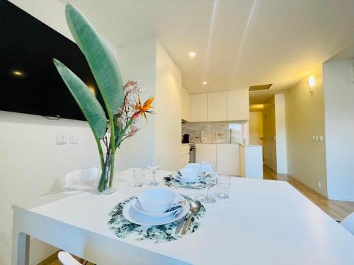 Una mesa blanca con un jarrón de flores. en Sweet Apartments Downtown en Vila Nova de Famalicão