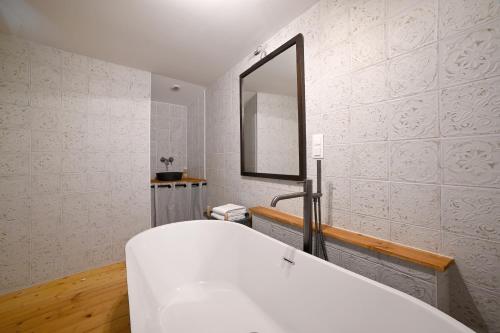 ein Badezimmer mit einer weißen Badewanne und einem Spiegel in der Unterkunft Mas des Gourmands in La Mothe-Saint-Héray