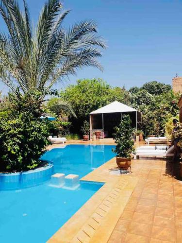 a large blue swimming pool with a tent in the background at Villa avec piscine in Marrakech