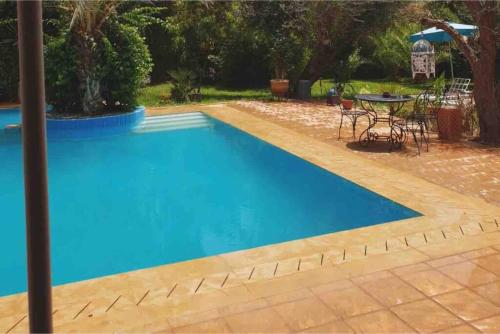 a blue swimming pool with a table in a yard at Villa avec piscine in Marrakech