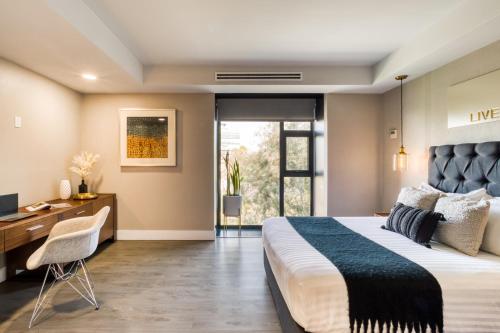 a bedroom with a large bed and a desk and a window at Eazy Rio by ULIV in Tijuana