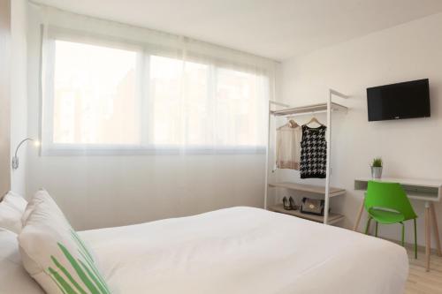a white bedroom with a bed and a window at SmartRoom Barcelona in Barcelona