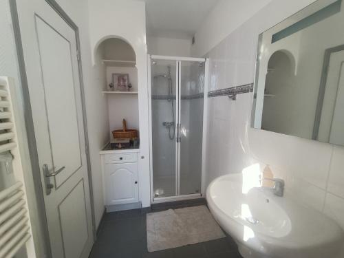 La salle de bains blanche est pourvue d'une douche et d'un lavabo. dans l'établissement Maison paisible avec parking, à Montpezat-de-Quercy