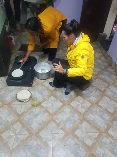 two people kneeling on the floor in a kitchen preparing food at Laxmi Homestay with main square view in Bhaktapur