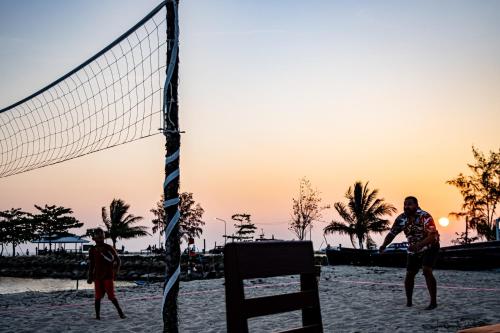 two men playing a game of volleyball on the beach at Villa Wonderworld Resort in Ban Nua