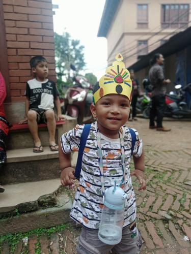 a young boy wearing a birthday hat holding a water bottle at Laxmi Homestay with main square view in Bhaktapur