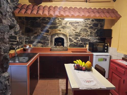 una cocina con fregadero y una mesa con fruta. en Casa Rosa, en Camacha