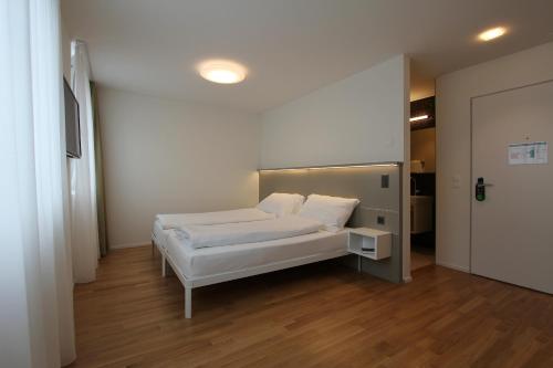 a bedroom with a white bed and a door at Hotel Flawil in Flawil