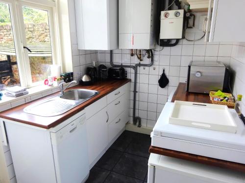 eine Küche mit weißen Schränken, einem Waschbecken und einem Fenster in der Unterkunft B&B Vierwinden in Vlissingen