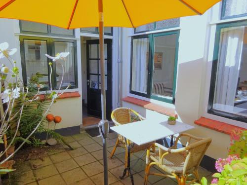 una mesa y sillas con una sombrilla en el patio en B&B Vierwinden, en Vlissingen