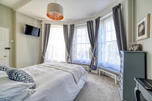 a bedroom with a bed and two windows at The Grove Cromer in Cromer