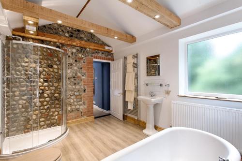 a bathroom with a shower and a tub and a sink at The Grove Cromer in Cromer