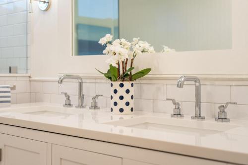 a bathroom sink with a vase with flowers in it at 1001 E Arctic Out of the Blue Stunning Oceanfront Home in Folly Beach