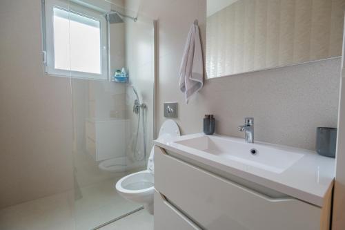 a white bathroom with a sink and a toilet at Apartment Aida in Sarajevo