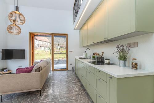una cocina con armarios blancos y un sofá en una habitación en Holiday House BALE, BALE, en Kostel