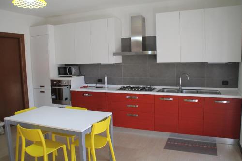 a kitchen with red and white cabinets and yellow chairs at CASA VACANZE DA RIKI APPARTAMENTO 1 in Peschiera del Garda