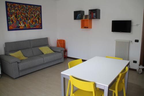 a living room with a couch and a table and yellow chairs at CASA VACANZE DA RIKI APPARTAMENTO 1 in Peschiera del Garda