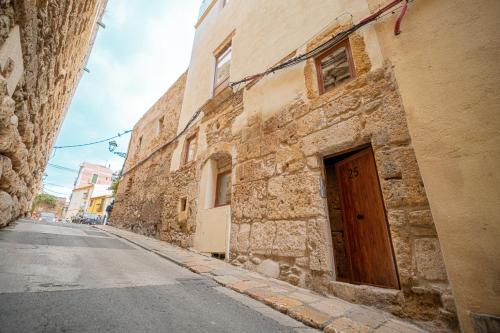 an old stone building with a wooden door on a street at Apartamento 23 en la muralla romana junto a la Catedral in Tarragona