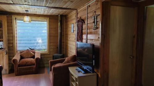 a living room with a tv and two chairs and a window at Cabañas Aguas Claras in Pinto