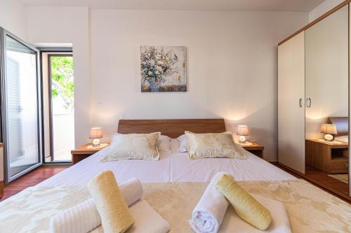 a bedroom with a large white bed with two pillows at Rajcic Apartments in Rogoznica