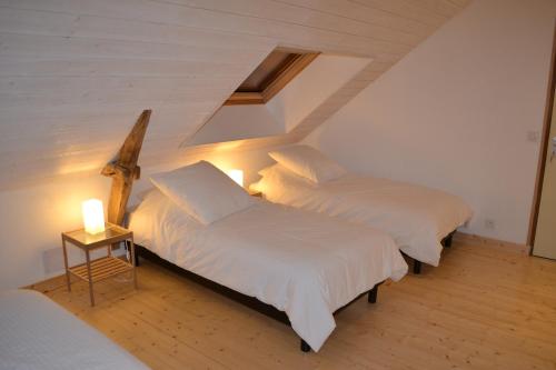 a bedroom with two beds and a table with a lamp at Le Chêne Blanc in Plessé