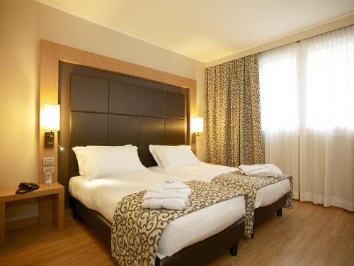 a hotel room with a large bed with towels on it at Virginia Palace Hotel in Garbagnate Milanese
