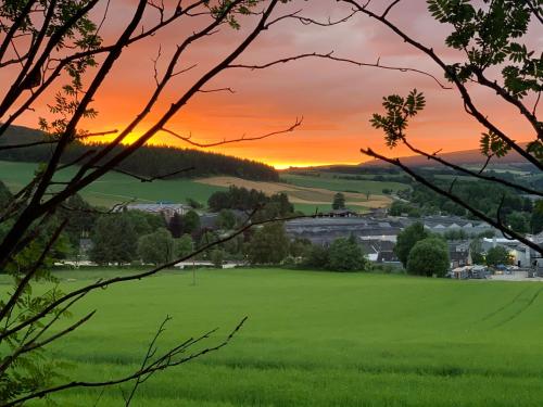 a green field with a sunset in the background at Inveravon Holiday Home in Dufftown