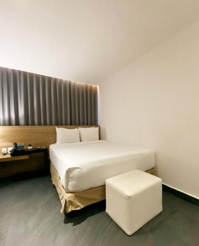 a bedroom with a large white bed and a stool at B's Suites Mérida in Mérida
