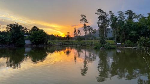 a body of water with a sunset in the background at Seu Refúgio Rural Piscina Privativa e Natureza in Tubarão