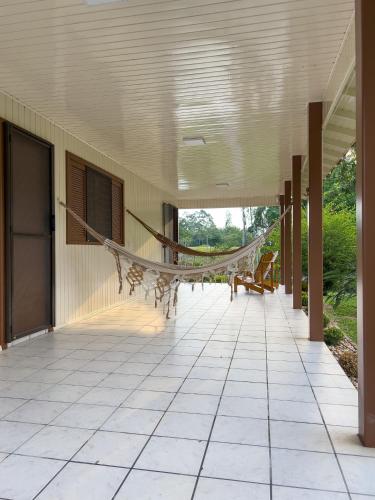 a porch with a hammock hanging from the ceiling at Seu Refúgio Rural Piscina Privativa e Natureza in Tubarão