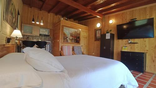 a bedroom with a white bed and a flat screen tv at CABAÑAS MONTEVERDE - Guarne ANT in Guarne