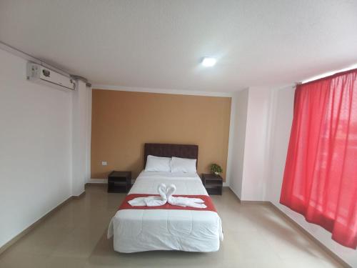 - une chambre avec un lit et un rideau rouge dans l'établissement HOTEL DIAMANTE, à Santo Domingo de los Colorados