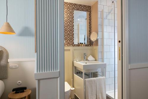 a bathroom with a sink and a toilet and a mirror at Le Petit Oberkampf Hotel & Spa in Paris