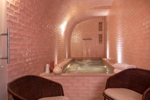 y baño con bañera de hidromasaje en una pared de ladrillo. en Le Petit Oberkampf Hotel & Spa, en París