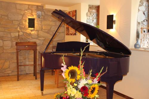 a black piano with a bunch of flowers at Romantik Hotel Chalet am Kiental in Herrsching am Ammersee