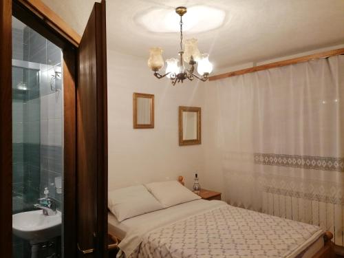 a bedroom with a bed and a sink and a chandelier at PLITVICE KONAK Daic in Plitvička Jezera