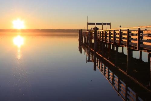 a pier with the sun setting over a body of water at Romantik Hotel Chalet am Kiental in Herrsching am Ammersee