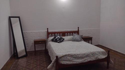 a bedroom with a bed with pillows and a mirror at HERMOSA CASONA ANTIGUA Y LUMINOSA in Villa María