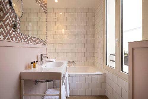 a white bathroom with a sink and a tub at Le Petit Oberkampf Hotel & Spa in Paris