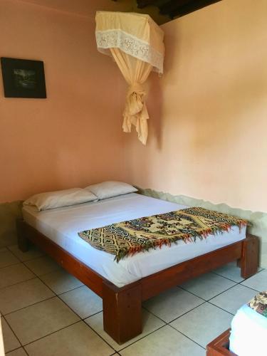 ein Bett in einem Zimmer mit einem Vorhang an der Wand in der Unterkunft Hostal Machalilla in Puerto López