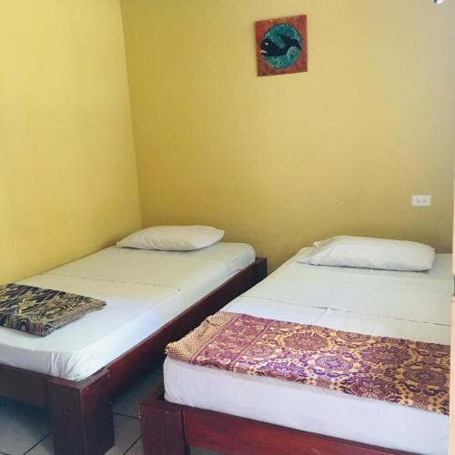 2 camas en una habitación con paredes amarillas en Hostal Machalilla, en Puerto López