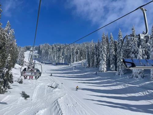 a ski lift with people skiing down a snow covered slope at Woodside Kopaonik & SPA by Slopeview in Kopaonik