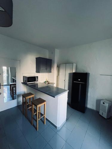 Il comprend une cuisine équipée d'un réfrigérateur noir, d'une table et de chaises. dans l'établissement So'Conciergerie - Joli studio idéalement situé., à Cassis