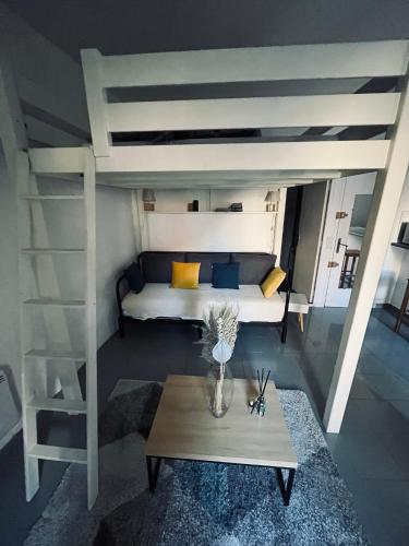 Cette chambre comprend un lit en mezzanine et une table. dans l'établissement So'Conciergerie - Joli studio idéalement situé., à Cassis