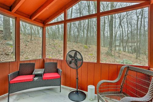 a screened in porch with two chairs and a fan at 4 Mi to Tubing Cozy Bushkill Cabin with Deck! in Bushkill
