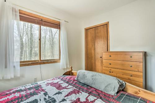 a bedroom with a bed and a dresser and a window at 4 Mi to Tubing Cozy Bushkill Cabin with Deck! in Bushkill