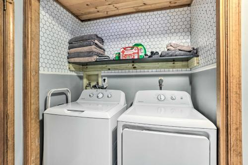 a laundry room with two white washing machines and a shelf at 4 Mi to Tubing Cozy Bushkill Cabin with Deck! in Bushkill