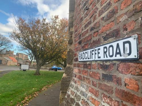 a street sign on the side of a brick wall at Brada View Bamburgh in Bamburgh